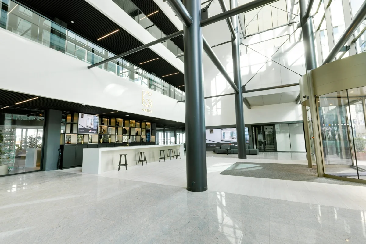 Moderne lobby van het Gaudi-gebouw met hoge plafonds en een centraal ingerichte balie.