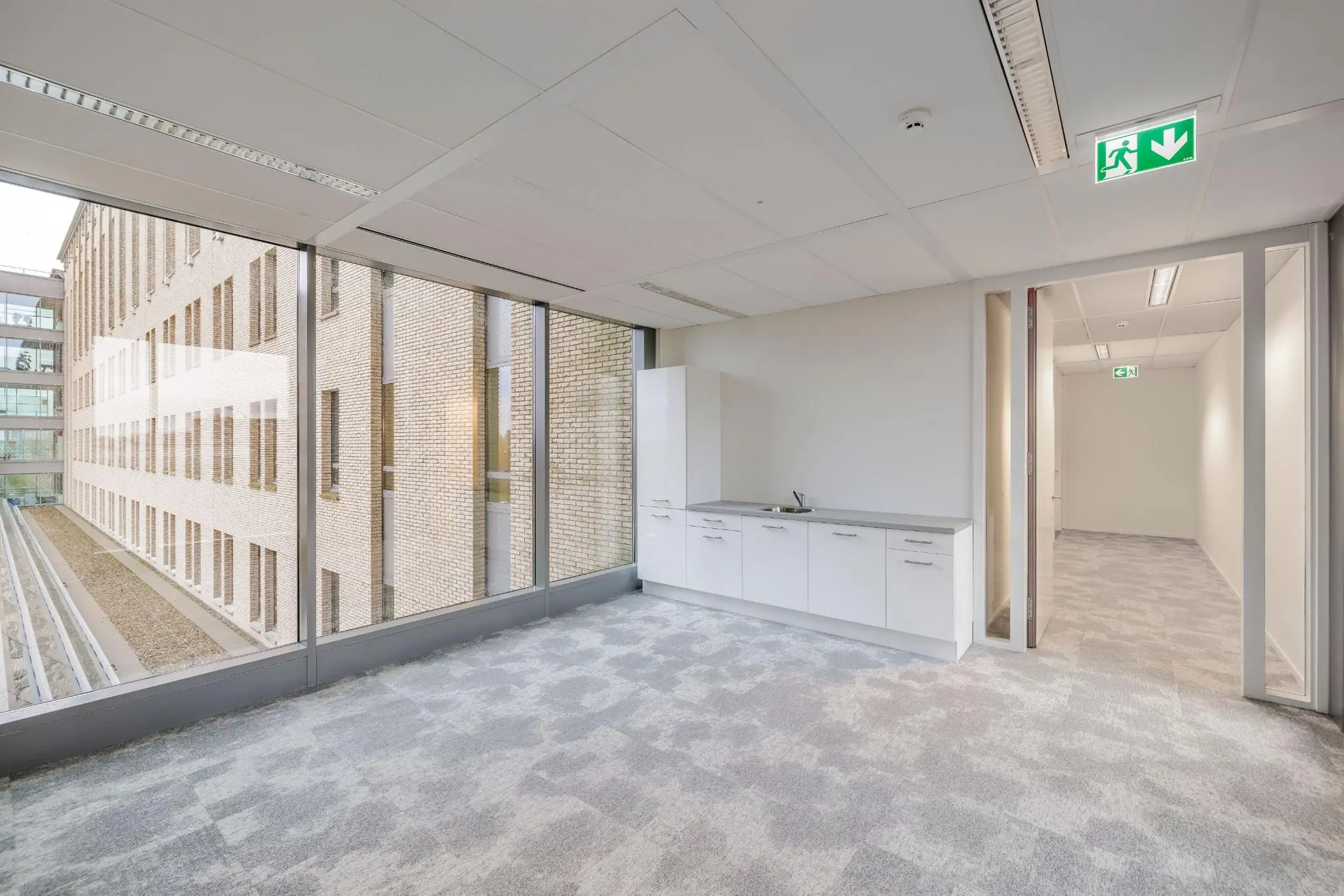 Moderne kantoorruimte aan de Mercatorlaan met pantry, grote raampartij en zicht op een aangrenzend kantoorgebouw.