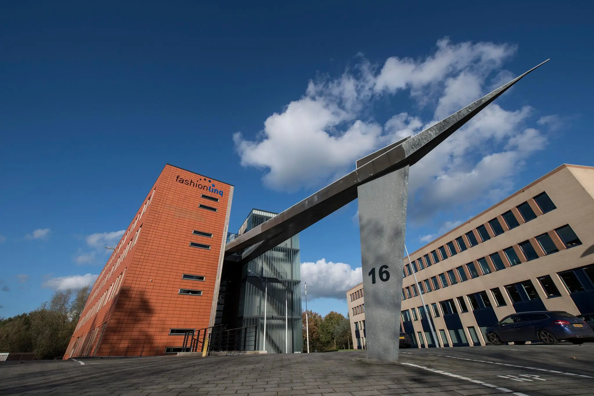 Modern kantoorgebouw aan de Fokkerstraat met het logo van FashionLinQ en een opvallende sculptuur met het nummer 16.