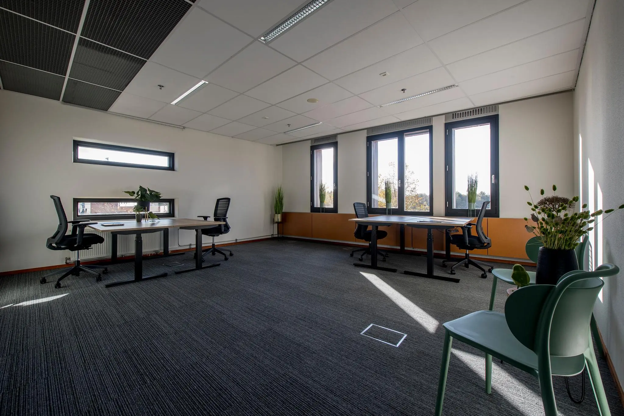 Modern ingericht kantoor aan de Fokkerstraat met bureaus, bureaustoelen en grote ramen die veel daglicht binnenlaten.