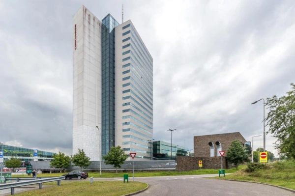 Hoog kantoorgebouw aan het Herculesplein in Utrecht met wolkenlucht op de achtergrond.