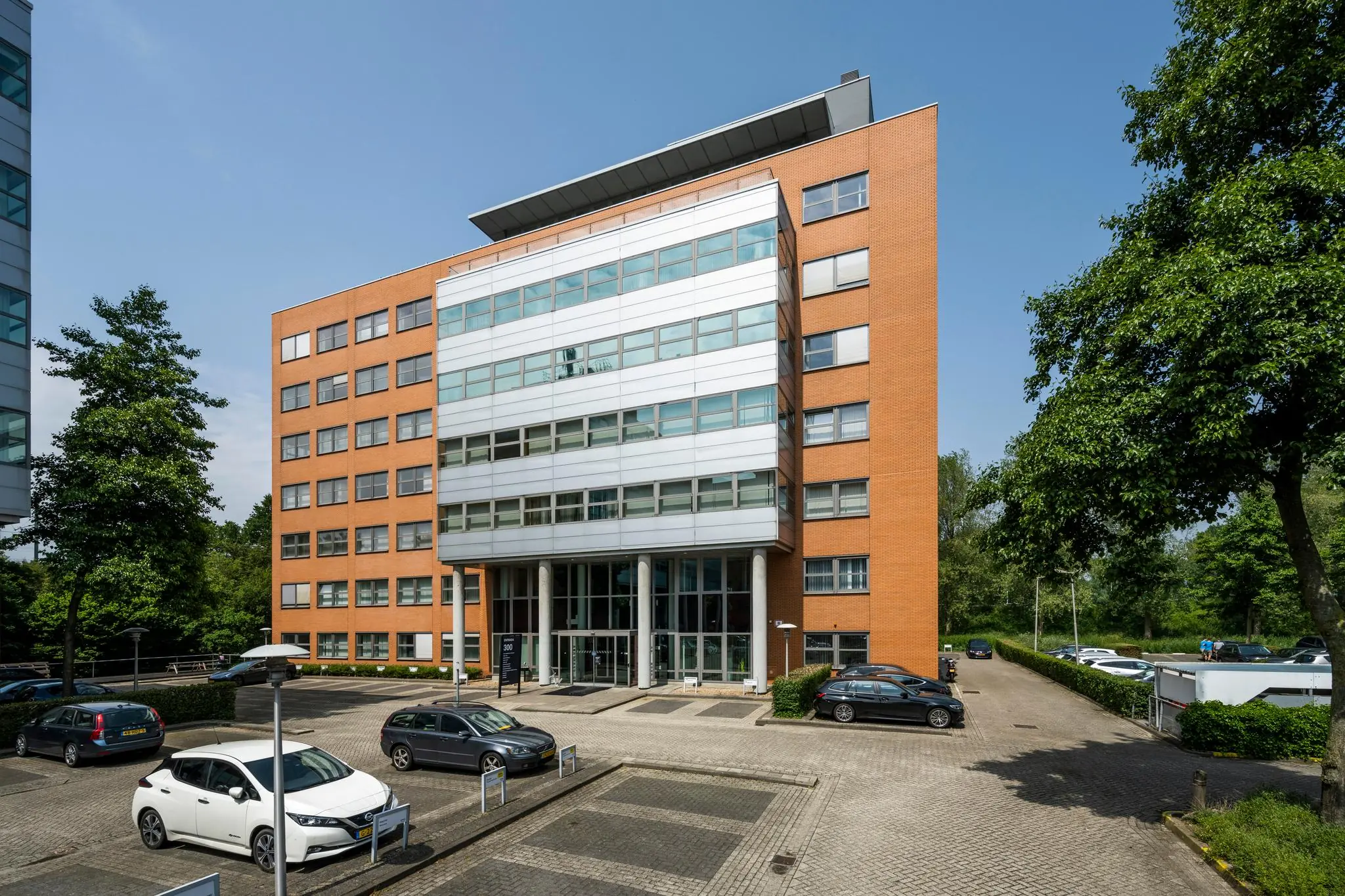 Moderne kantoorgebouw Entrada 165 met parkeergelegenheid aan de voorzijde op een zonnige dag.