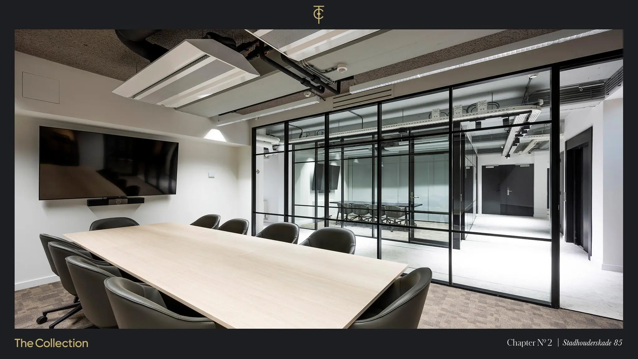 Moderne vergaderruimte aan de Stadhouderskade 85 met glazen wand, grote tafel, stoelen en flatscreen.