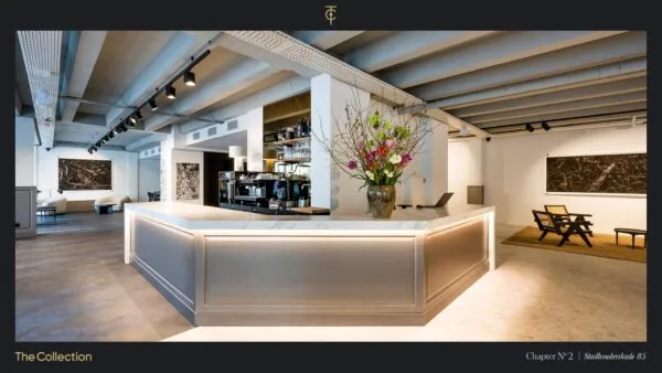 Modern en stijlvol interieur van een showroom aan de Stadhouderskade 85 met een marmeren ontvangstbalie, kunst aan de muren en een grote bloemenvaas.