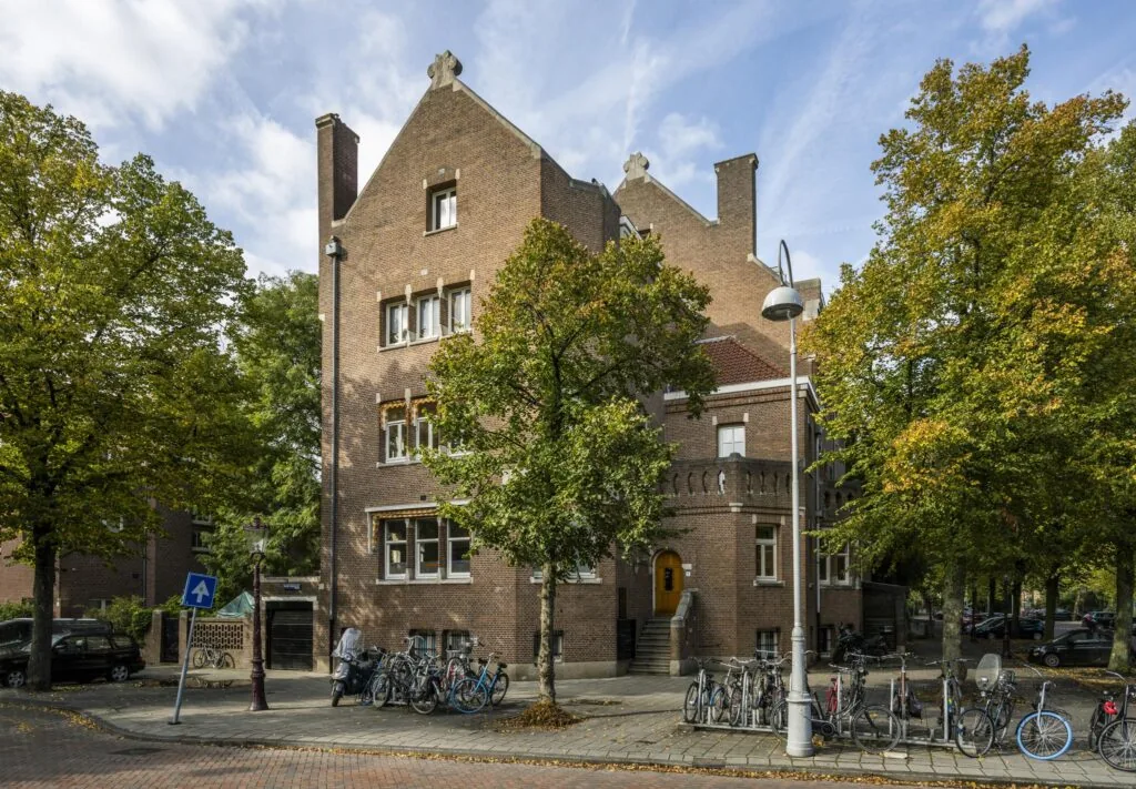 Hoekpand aan de Emmalaan met bakstenen gevel, trapgevels, en omringd door fietsen en bomen.