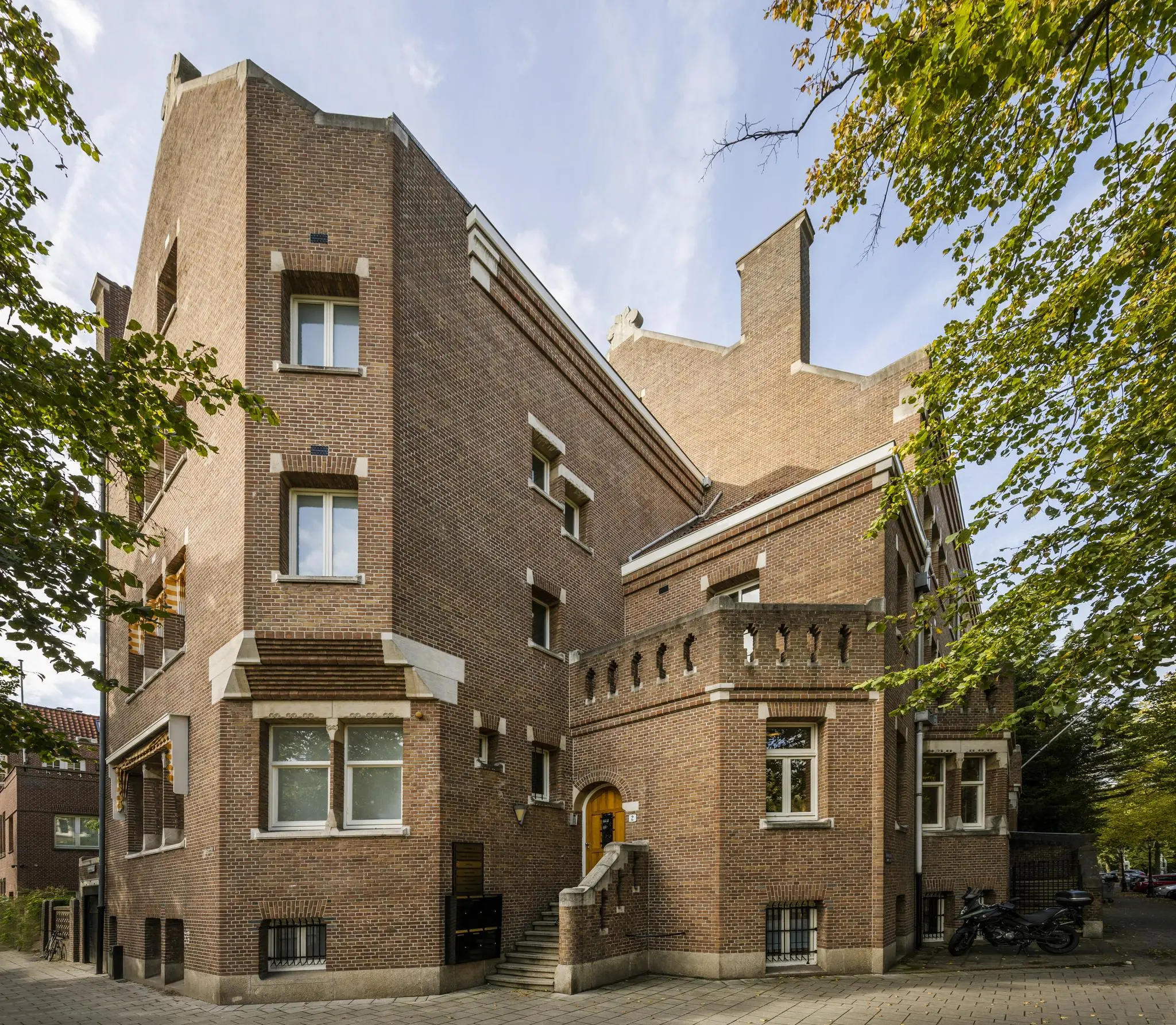 Hoekpand aan de Emmalaan met bakstenen gevel, sierlijke elementen en een trap naar de entree.