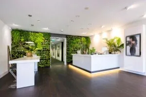 Moderne en frisse ontvangstruimte met groene plantenwand en witte balie bij Stammerhove.