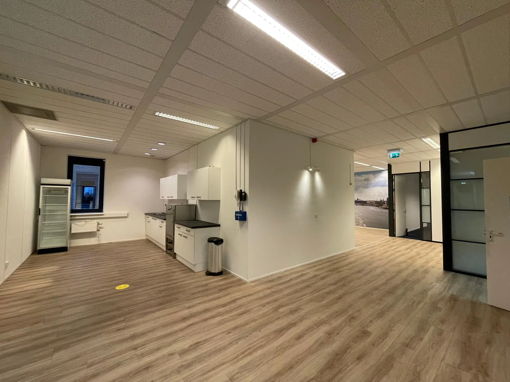 Moderne kantoorruimte aan de Zekeringstraat met open keuken, glazen deuren en houtlook vloer.