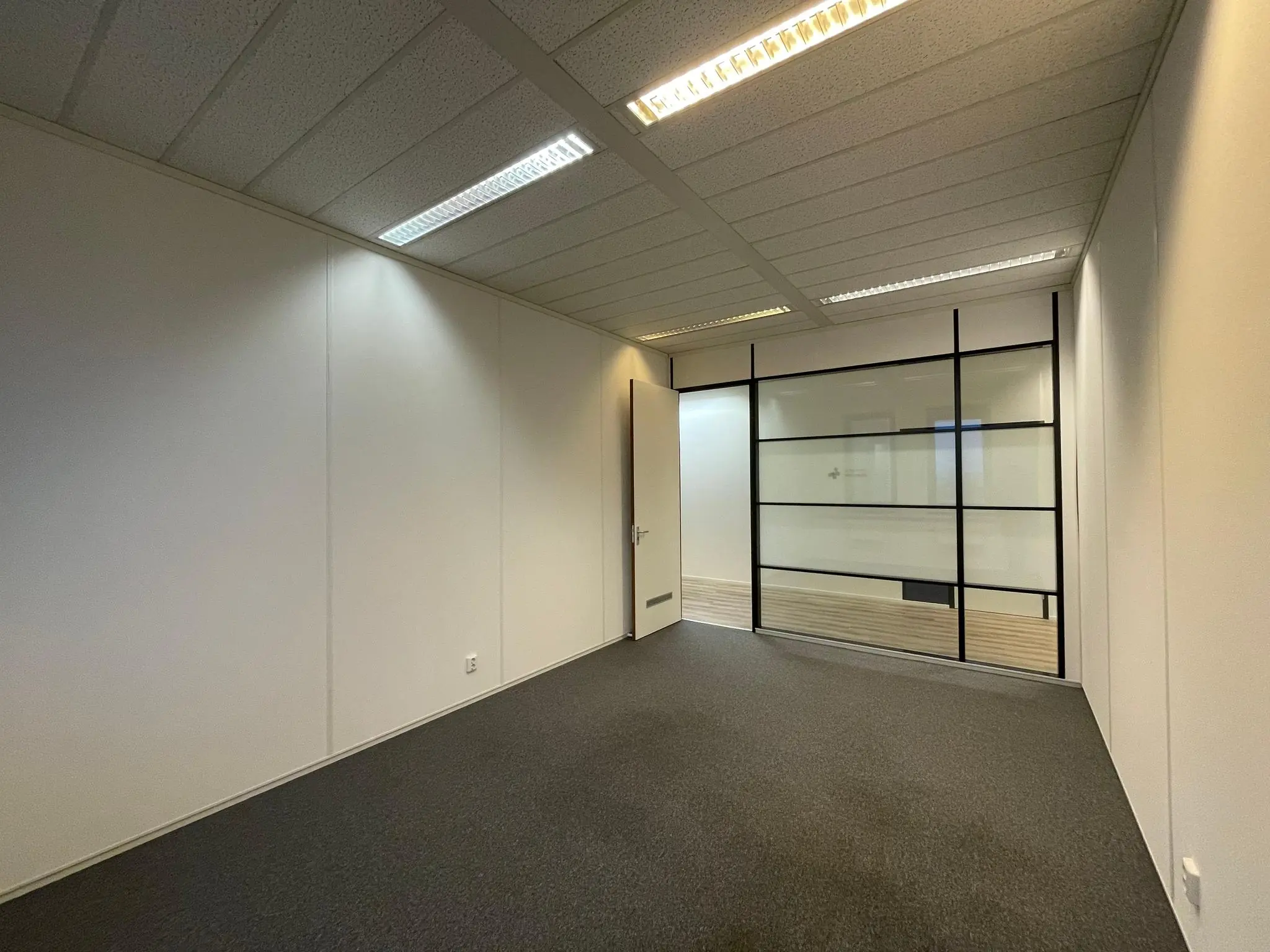 Lege kantoorruimte aan de Zekeringstraat met glazen binnenwand en systeemplafond.
