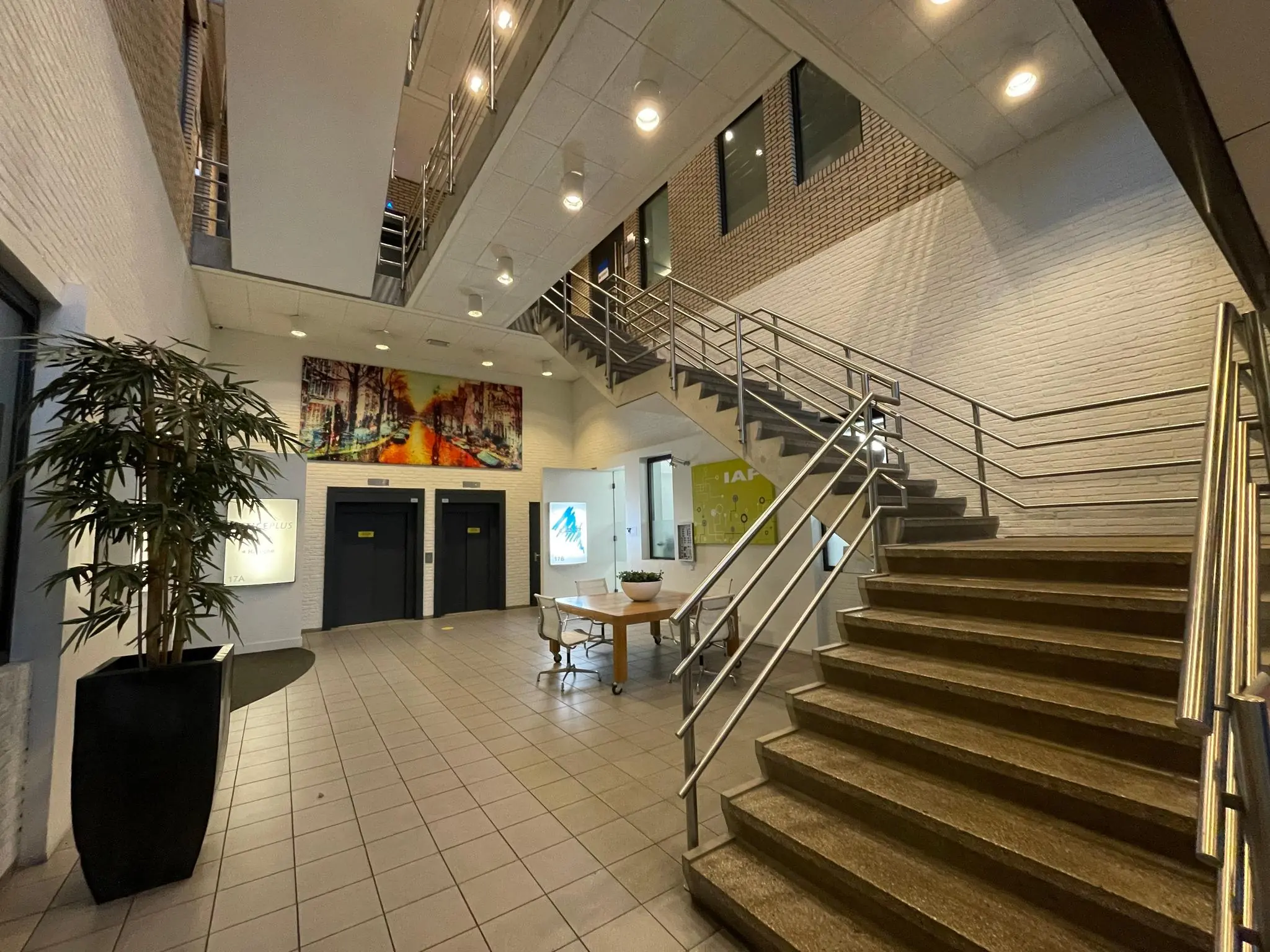 Moderne entreehal aan de Zekeringstraat met een trap, twee liften en een grote wandafbeelding.