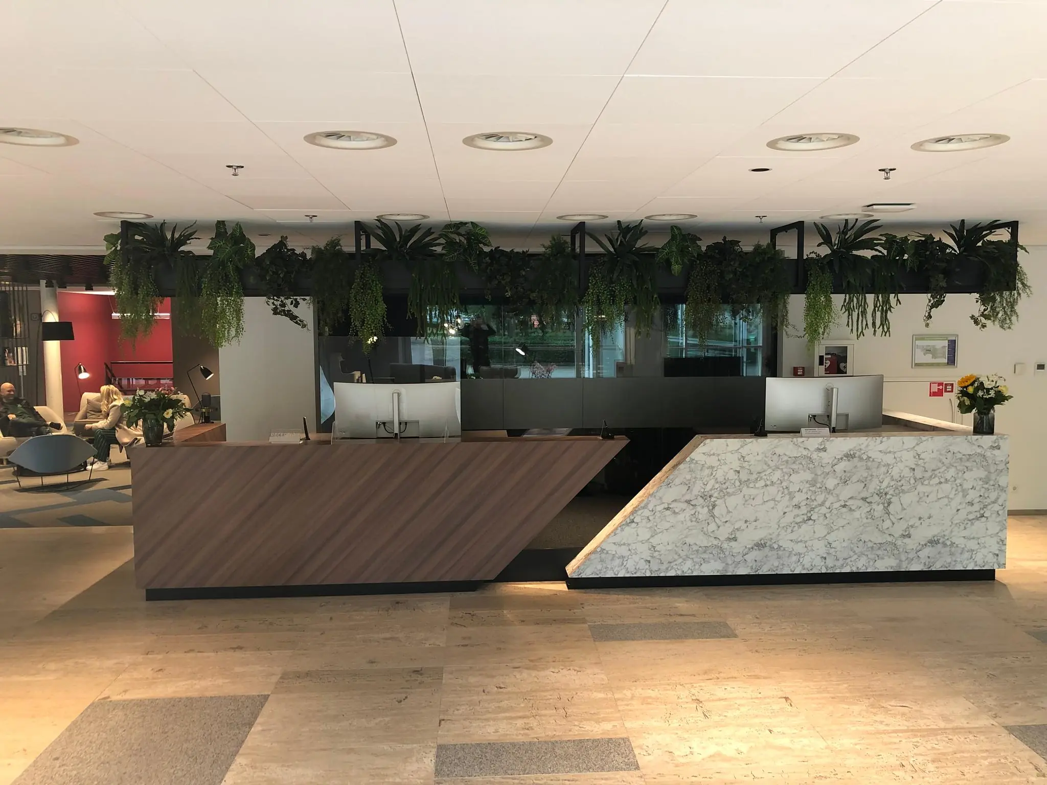Moderne receptiebalie met hout- en marmerafwerking in de entree van een kantoorpand aan de Newtonlaan.