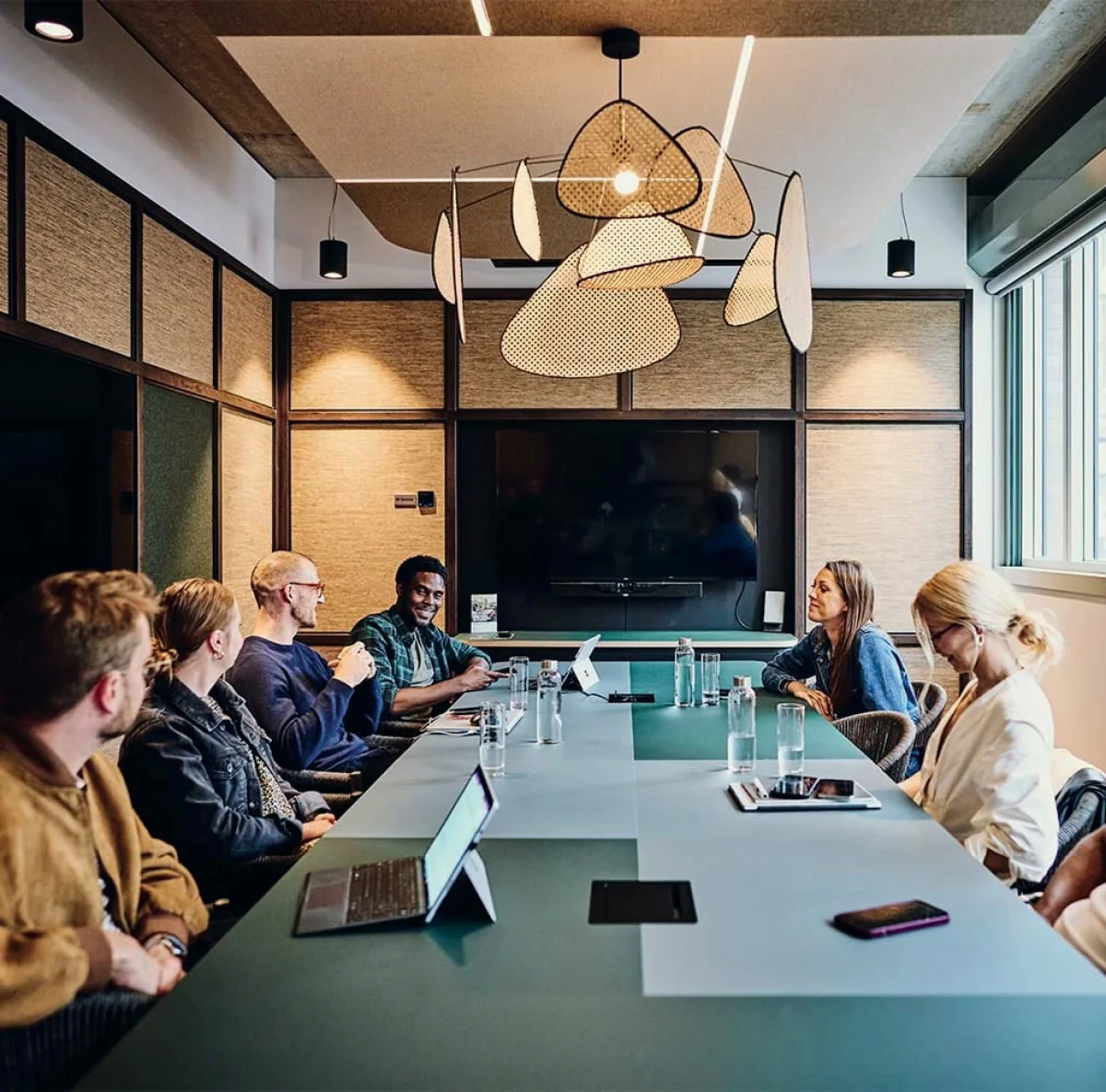 Een groep mensen zit rond een conferentietafel in een moderne vergaderruimte.