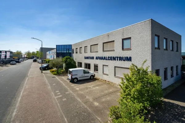 Voorgevel van het bedrijfspand "Sanitair Afhaalcentrum" aan de Daltonstraat met een geparkeerde witte bestelwagen.