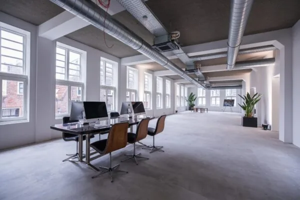 Modern en licht kantoorinterieur aan de Prins Hendrikkade met werkplekken, grote ramen en industriële details.