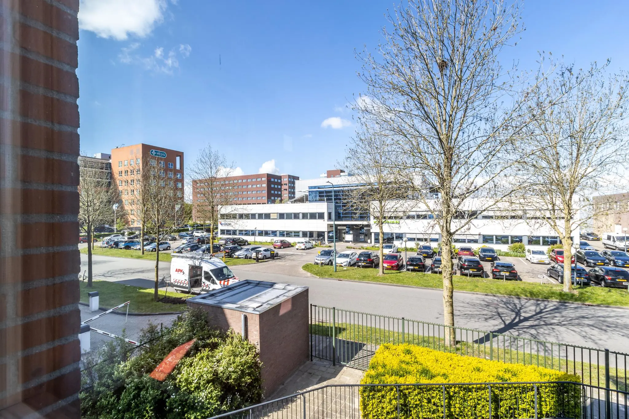 Uitzicht op het kantoorgebouw Veldzigt met parkeerterrein en omliggende kantoren op een zonnige dag.