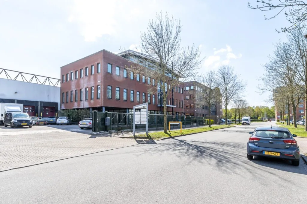 Kantoorgebouw Veldzigt 3 in een zakelijke omgeving met geparkeerde auto's en bomen langs de straat.