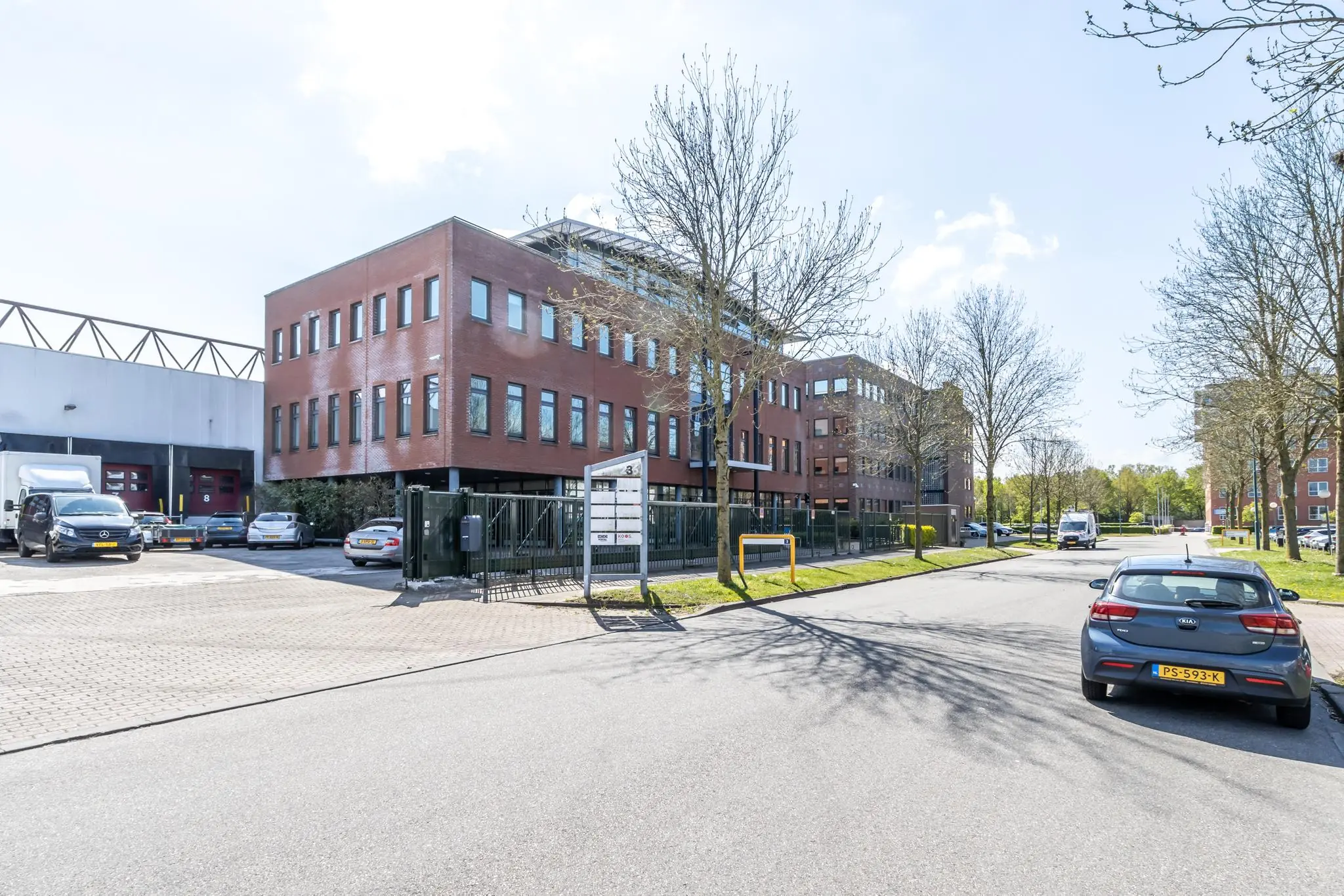 Kantoorgebouw Veldzigt 3 in een zakelijke omgeving met geparkeerde auto's en bomen langs de straat.