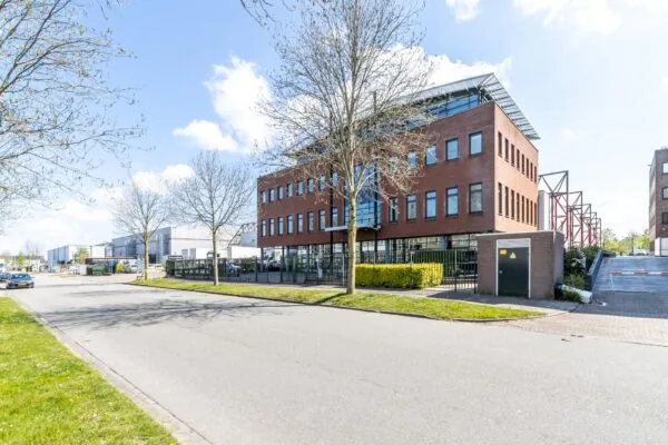 Modern kantoorgebouw aan de Veldzigtweg op een zonnige dag, omgeven door bedrijventerrein en jonge bomen.