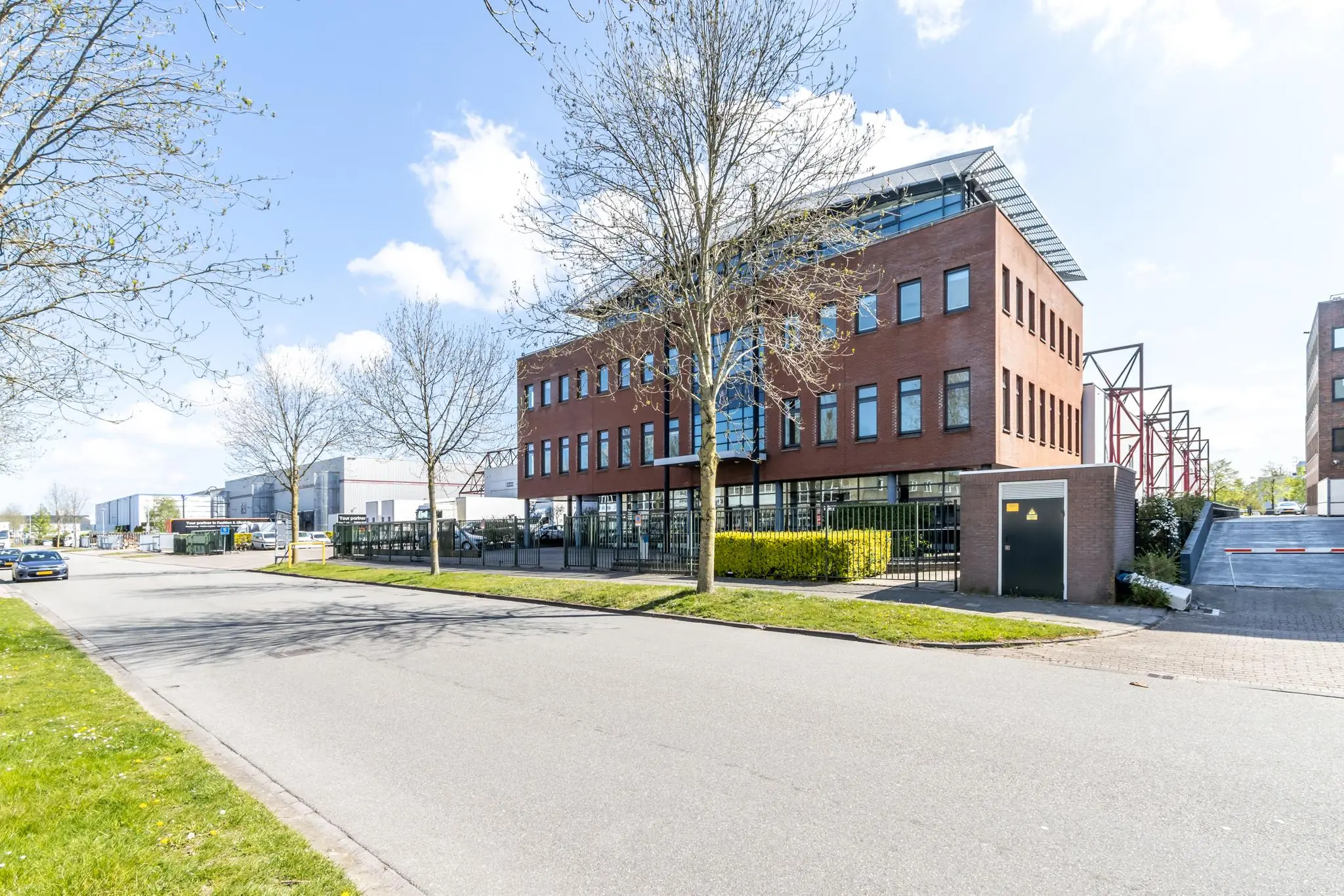 Modern kantoorgebouw aan de Veldzigtweg op een zonnige dag, omgeven door bedrijventerrein en jonge bomen.