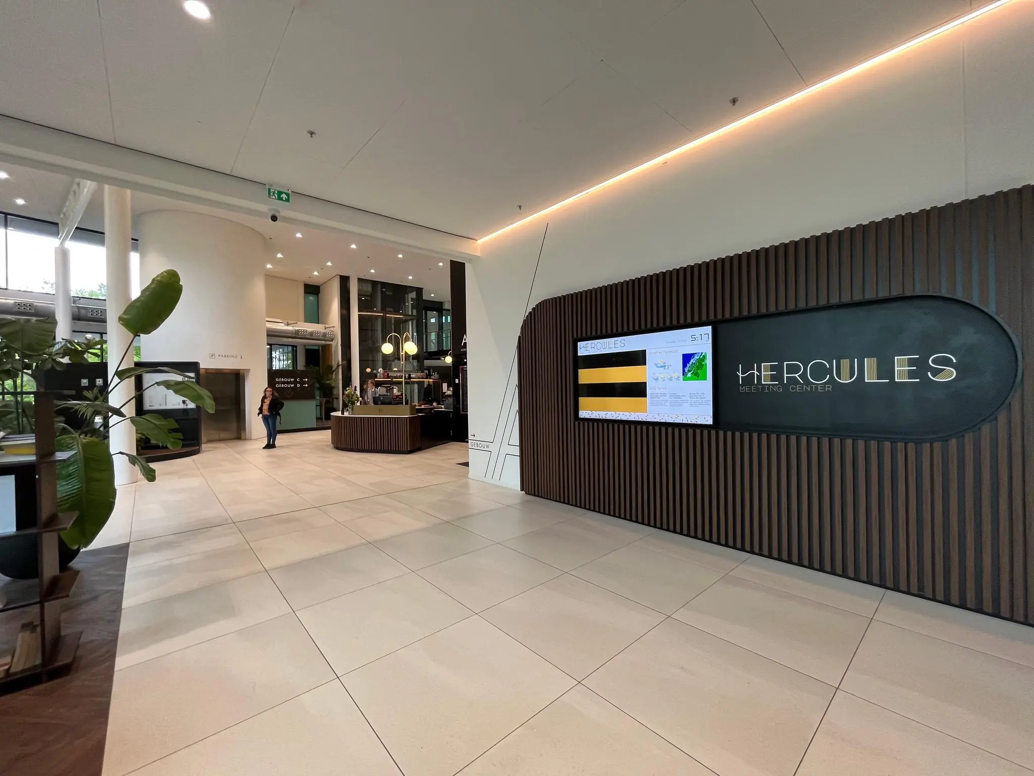 Moderne entree van het Hercules Meeting Center met een digitale informatiezuil en receptiebalie.