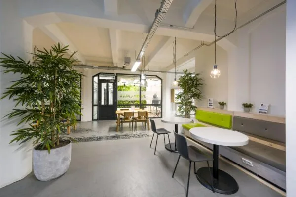 Moderne wachtruimte aan de Van Diemenstraat met groene accenten, zitbanken, tafels en veel planten.