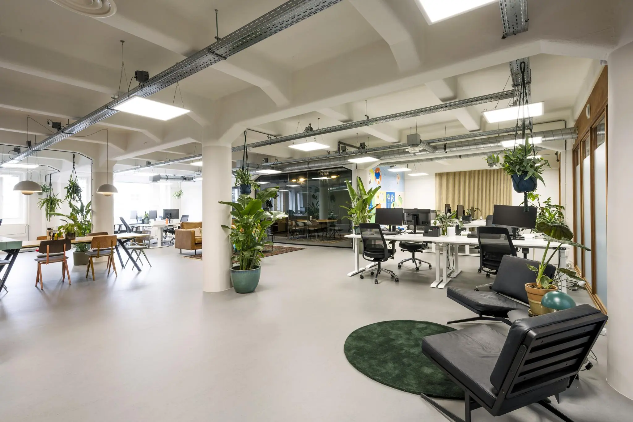Modern en ruim kantoorinterieur aan de Van Diemenstraat met open werkplekken, groene planten en een glazen vergaderruimte.