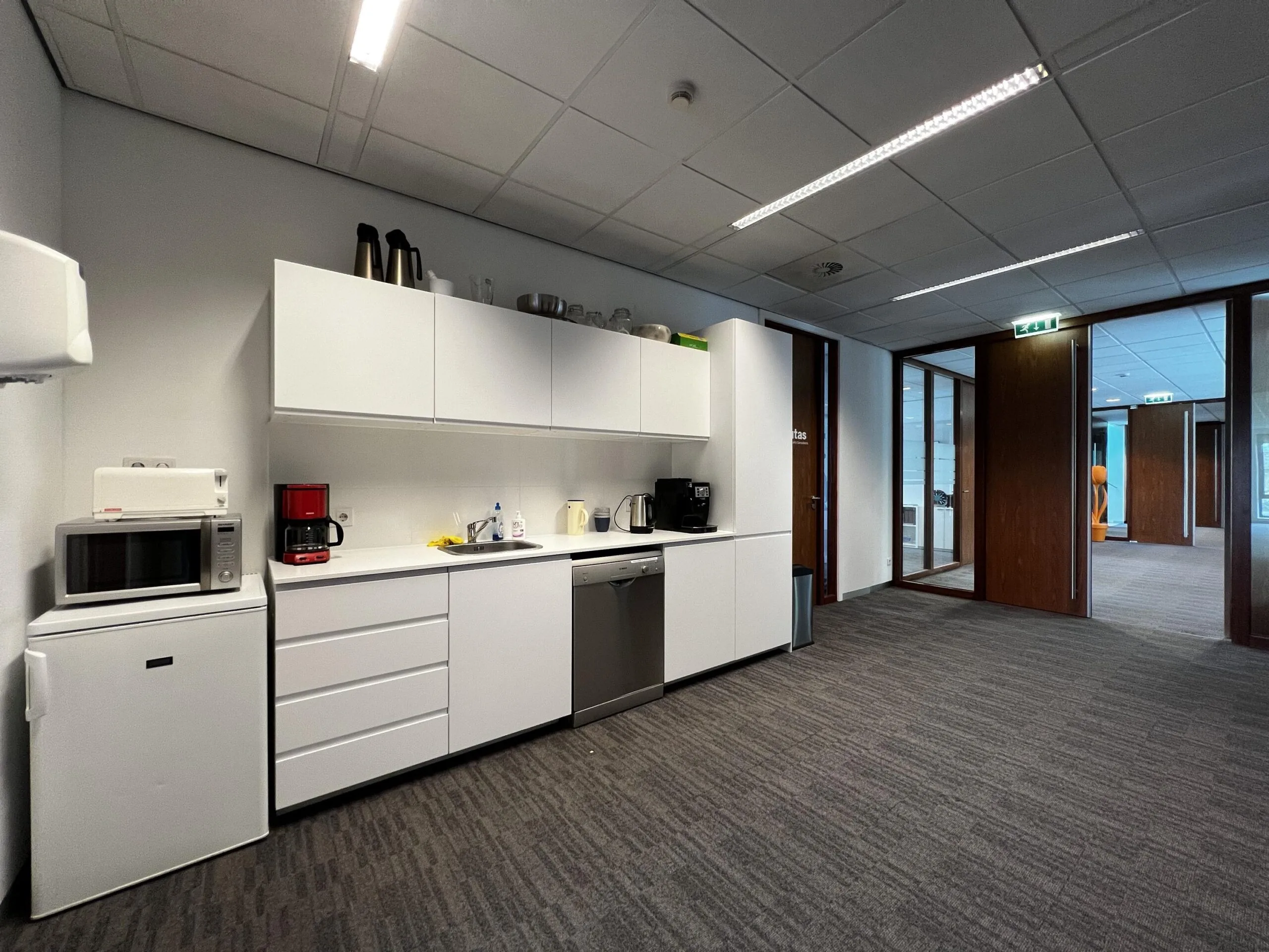 Een moderne kantoorpantry met witte keukenapparatuur en opbergruimte aan de Groenekanseweg.