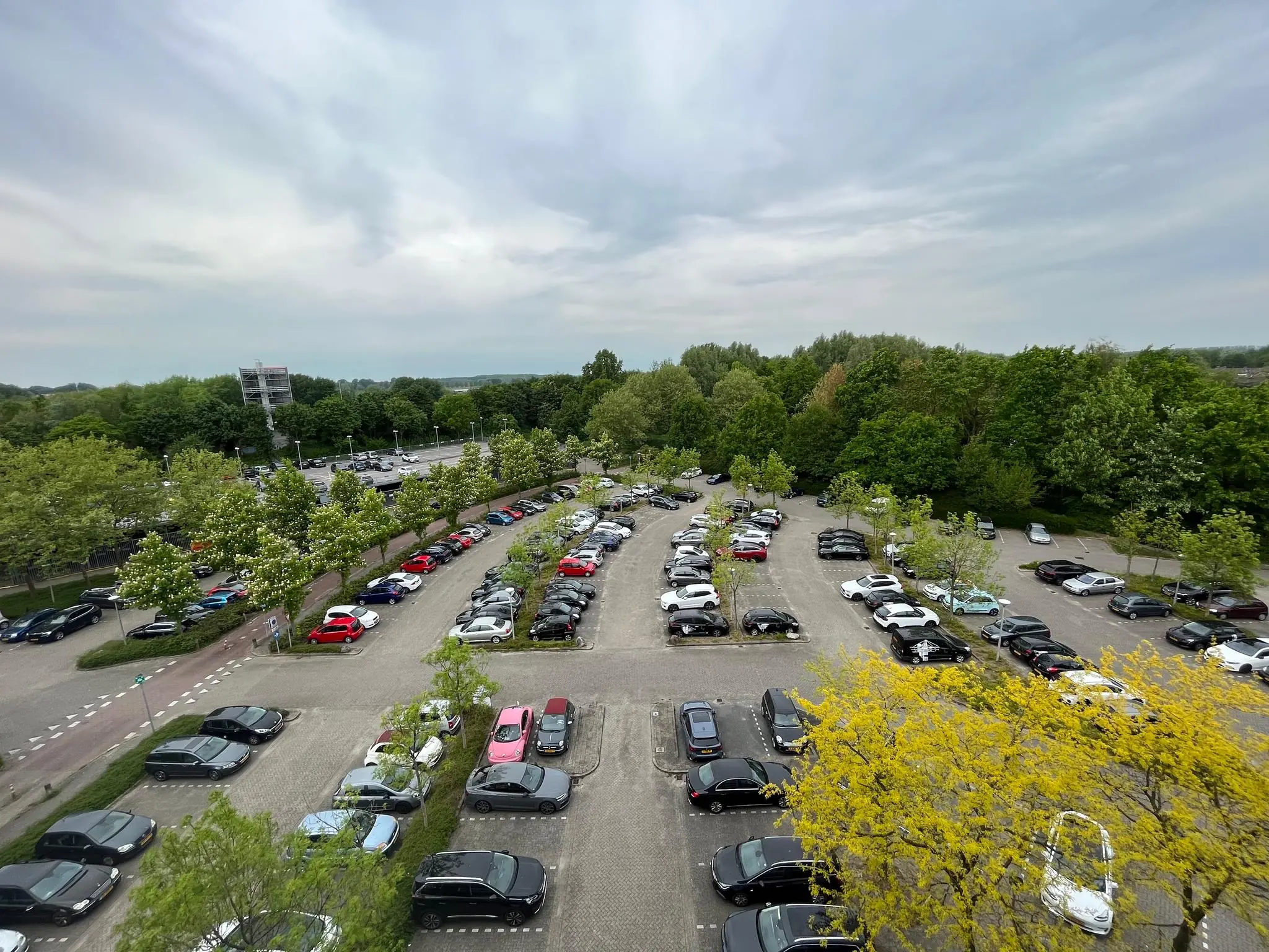 Overzicht van een parkeerplaats aan de Nevelgaarde, omgeven door bomen en geparkeerde auto's.