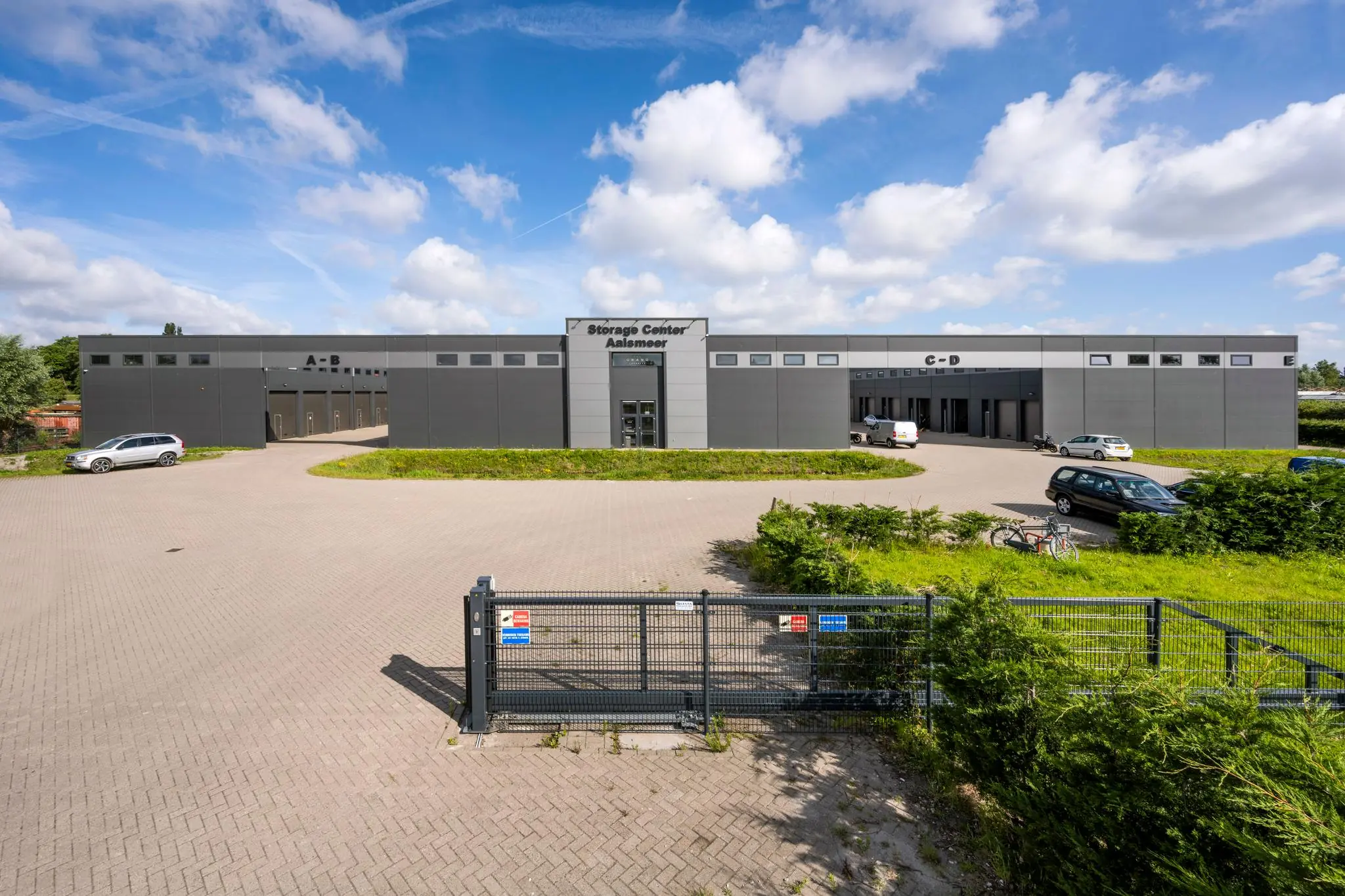 Grijs bedrijfsgebouw genaamd "Storage Center Aalsmeer" met meerdere ingangen en een afgesloten parkeerterrein.