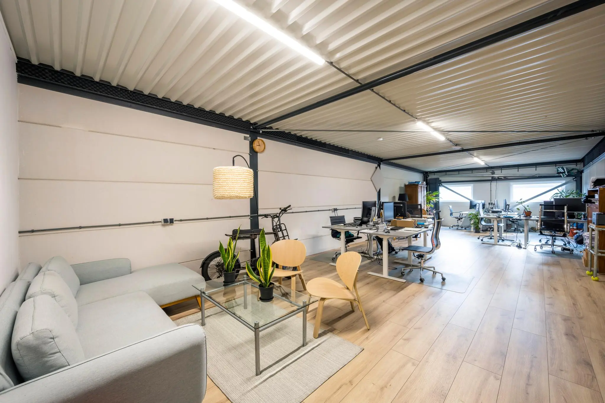 Modern ingerichte kantoorruimte aan de Aalsmeerderweg met werkplekken, zithoek en houten vloer.