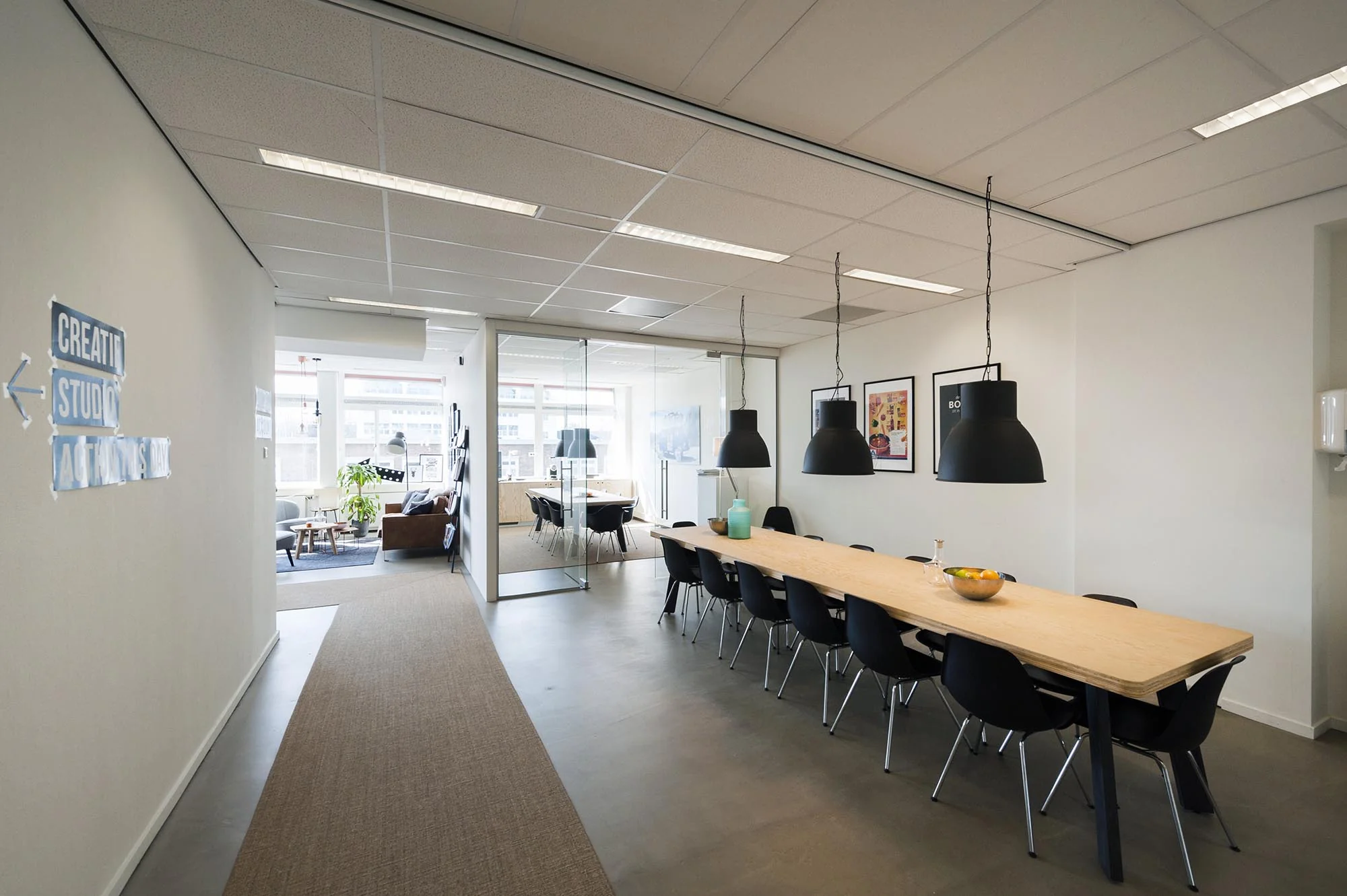Moderne kantoorruimte aan de Helicopterstraat met lange vergadertafel, zwarte stoelen en glazen vergaderruimte.
