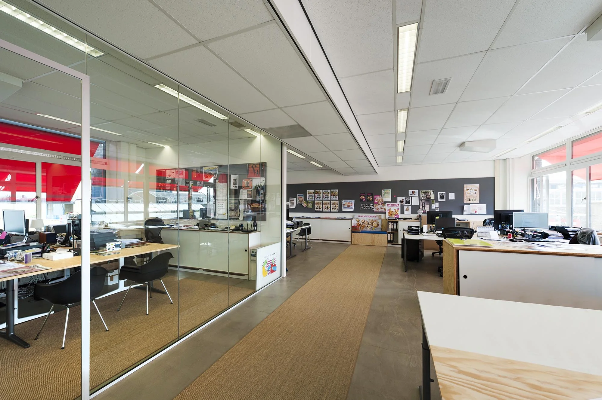 Modern kantoorinterieur aan de Helicopterstraat met glazen vergaderruimte en open werkplekken.