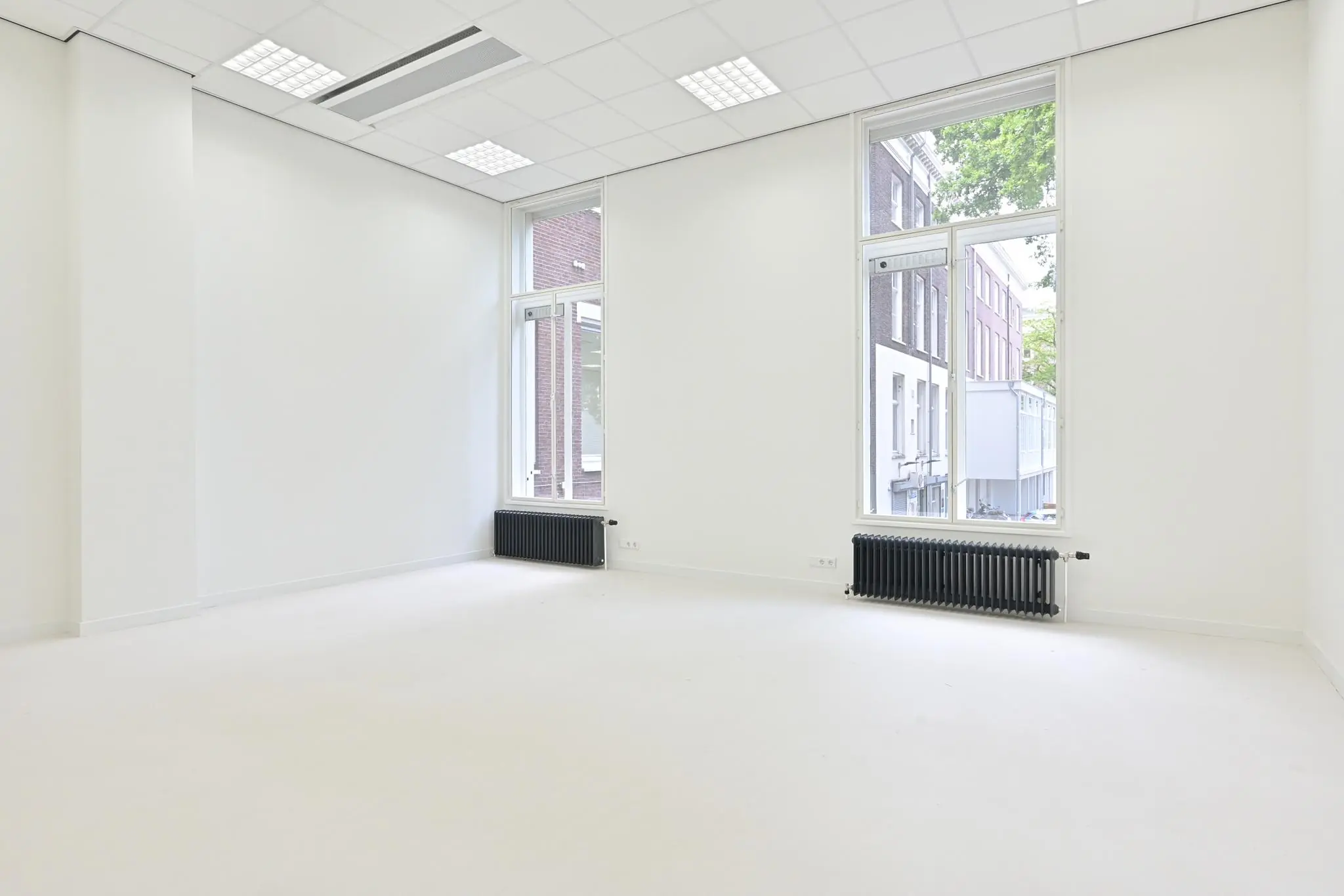 Licht en leeg kantoor aan de Parkstraat met hoge ramen en witte muren.