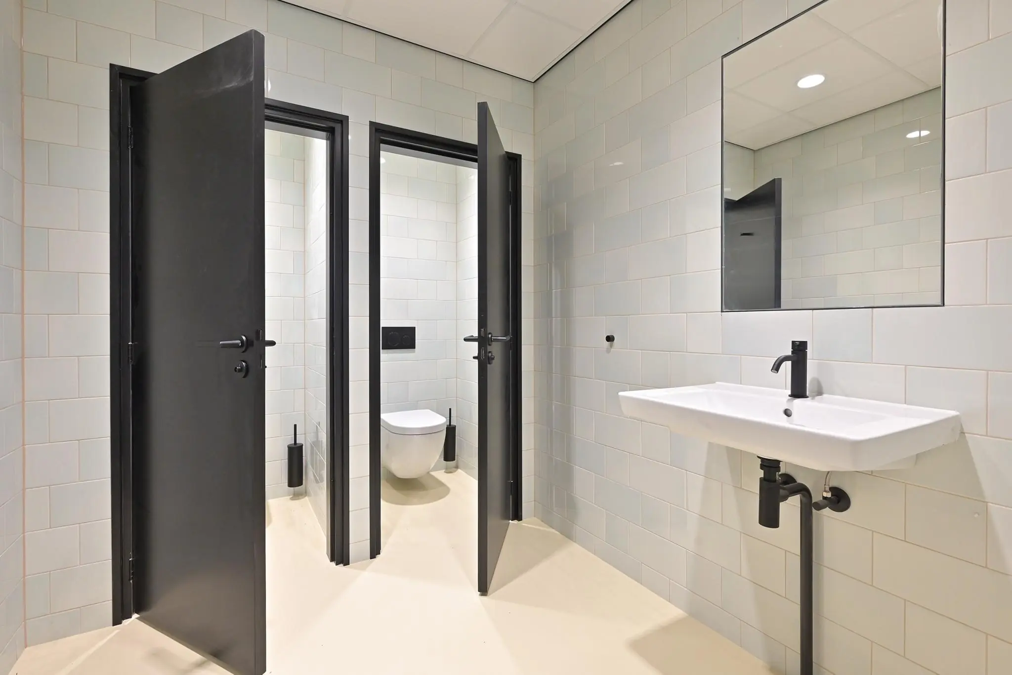 Moderne sanitaire ruimte met twee toiletten en een wastafel aan de Parkstraat.