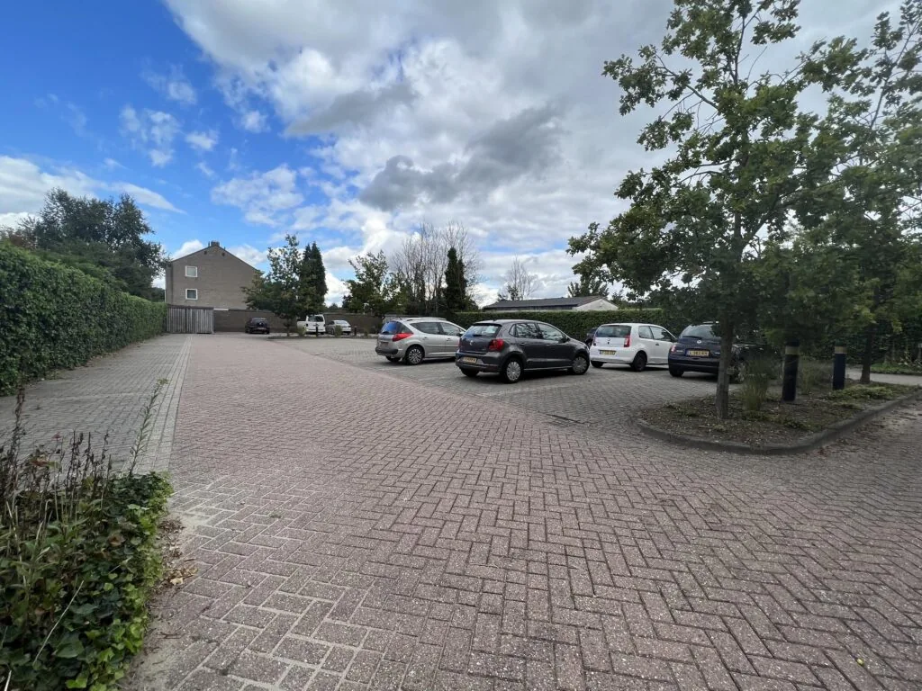 Parkeerplaats aan de Groenekanseweg met meerdere geparkeerde auto's en een huis op de achtergrond.