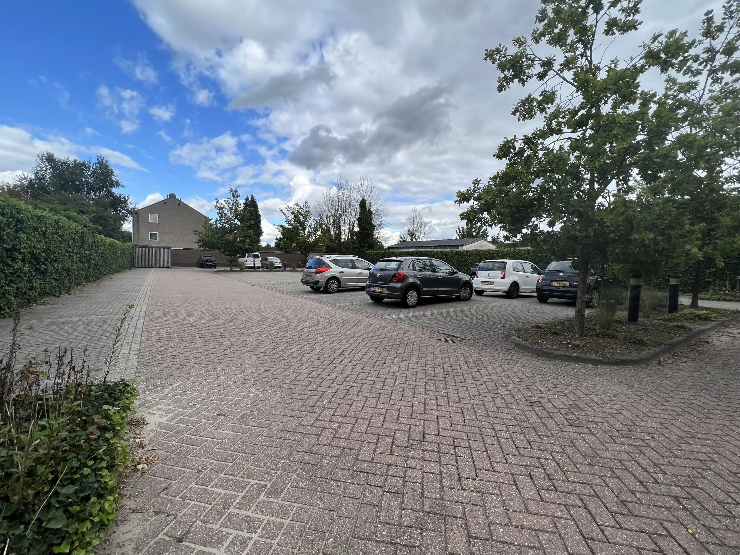 Parkeerplaats aan de Groenekanseweg met meerdere geparkeerde auto's en een huis op de achtergrond.