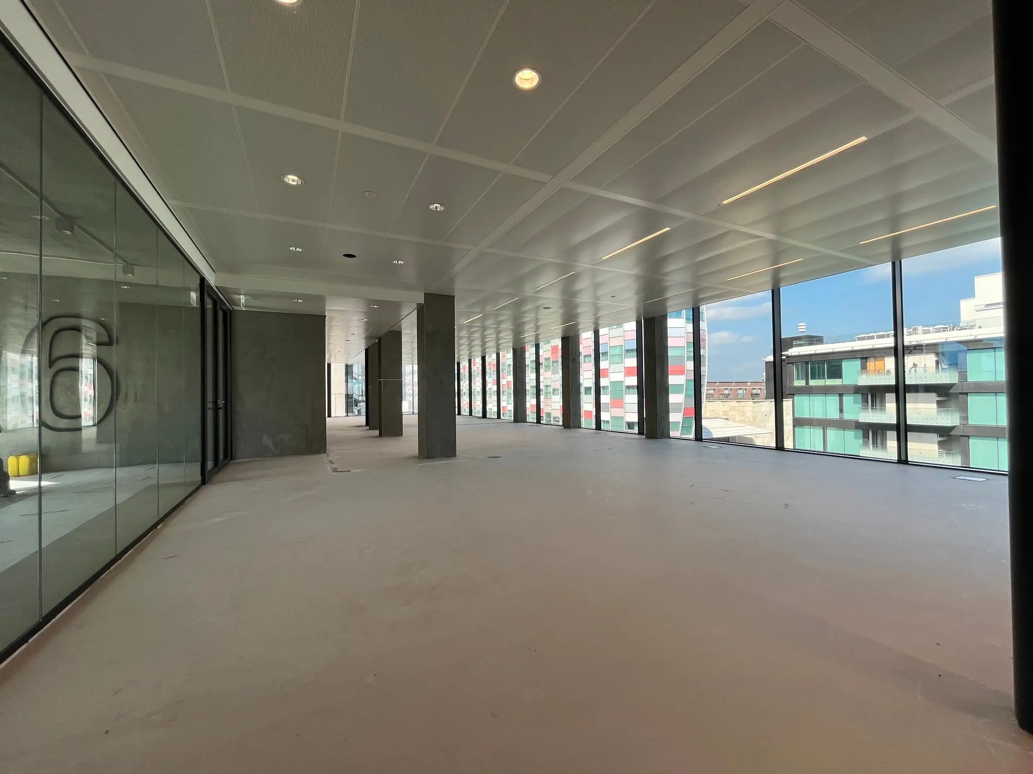 Leeg kantoorpand met glazen wanden en uitzicht op moderne gebouwen aan de Catharijnesingel in Utrecht.