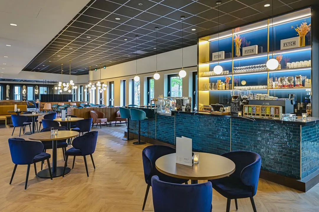 Modern ingerichte koffiebar aan de Kingsfordweg met blauwe tegels, fluwelen stoelen en sfeervolle verlichting.