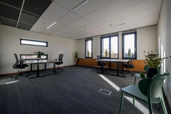 Modern en licht kantoor aan de Fokkerstraat met meerdere werkplekken, bureaustoelen en grote ramen.