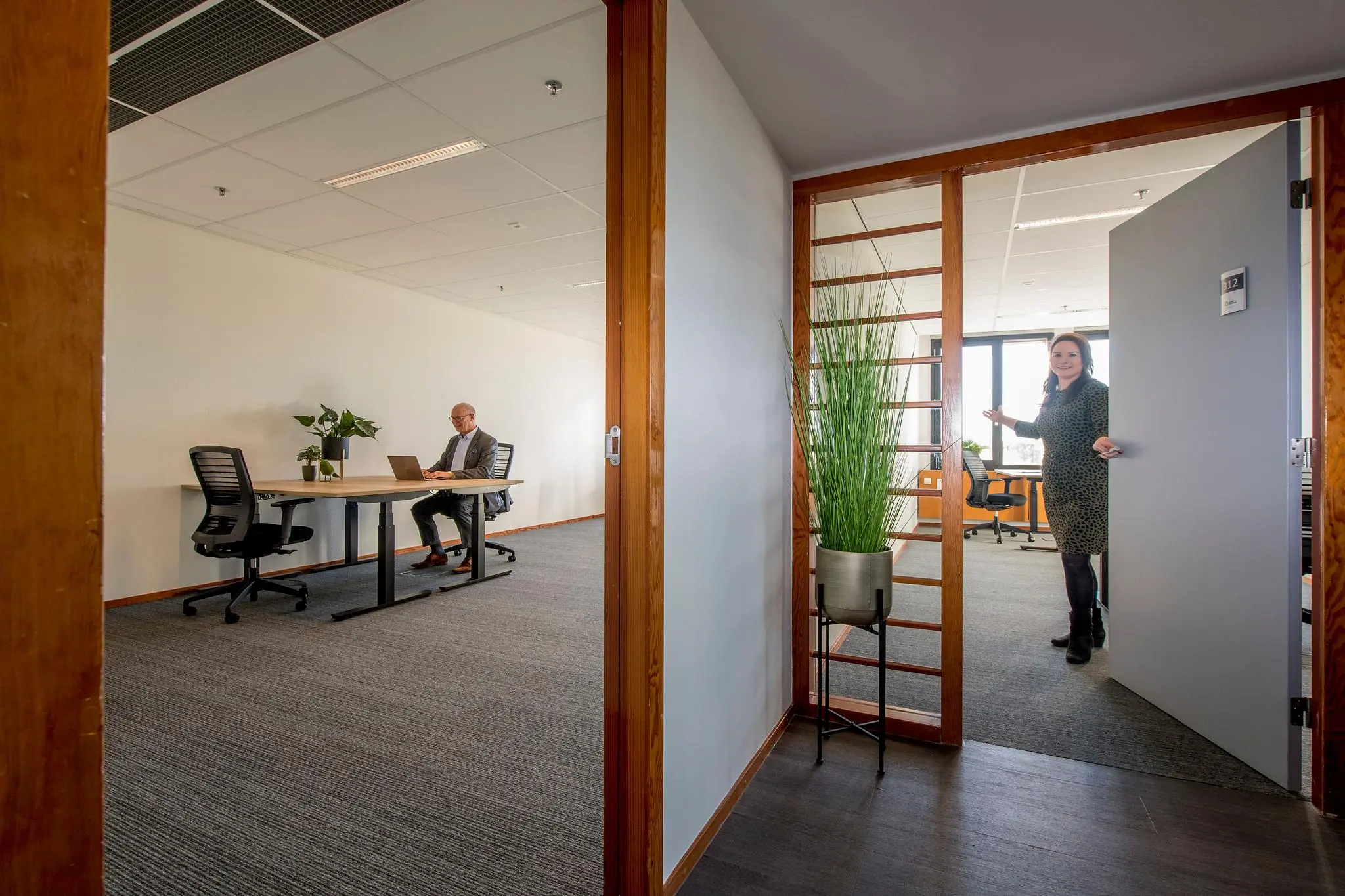 Kantoorruimte aan de Fokkerstraat met een man achter een bureau en een vrouw die een deur opent.