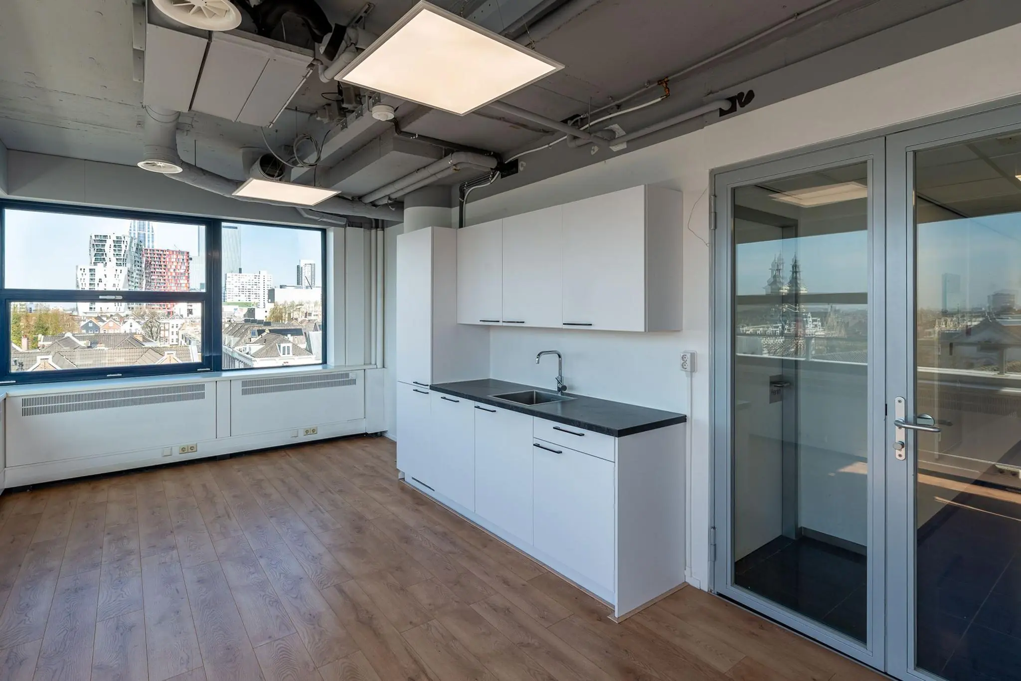 Moderne kantoorruimte aan de Westblaak met pantry, houten vloer en uitzicht op de skyline van Rotterdam.