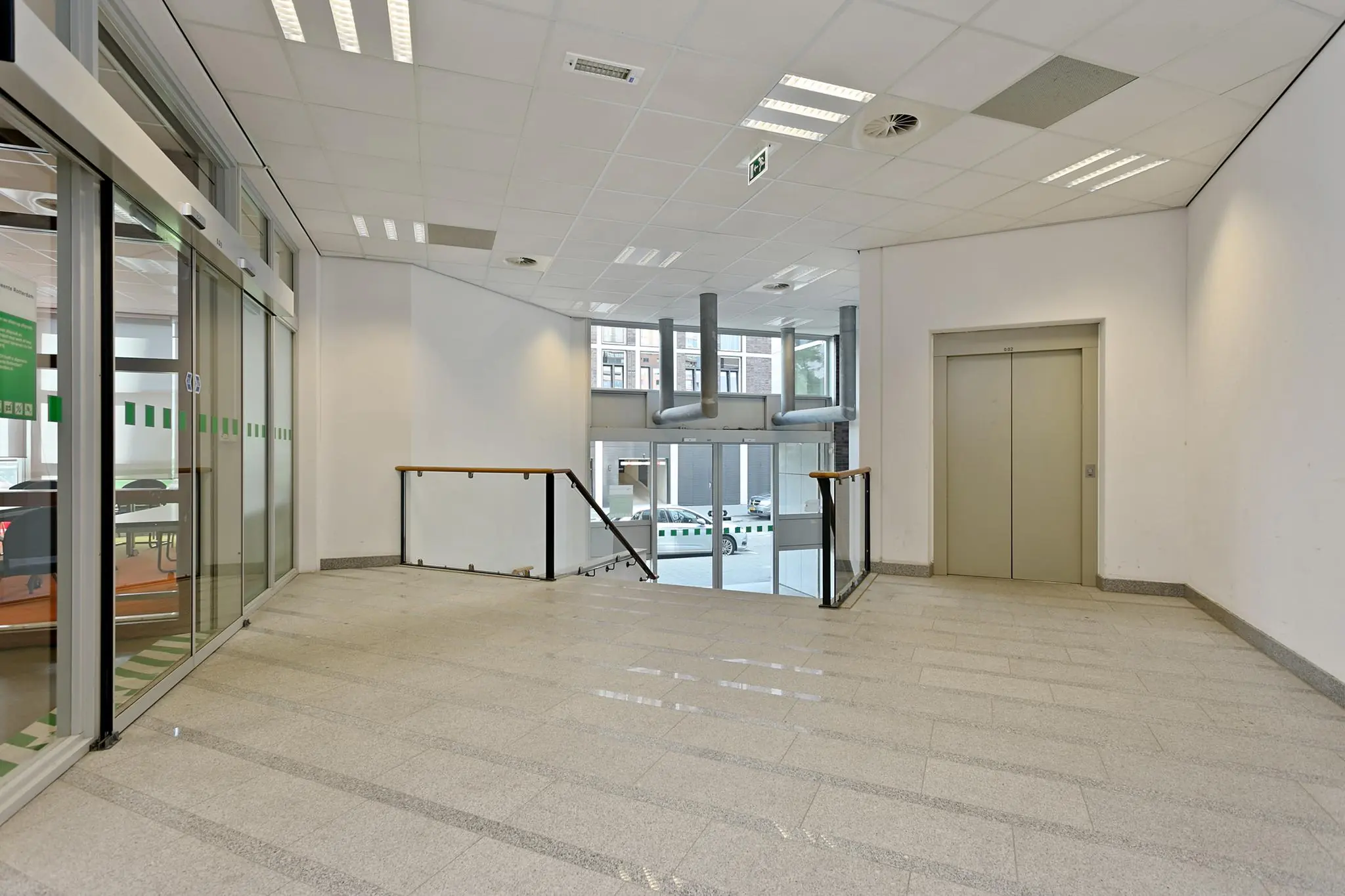 Moderne entreehal met een lift, glazen schuifdeuren en een trap naar de begane grond aan de Dynamostraat.