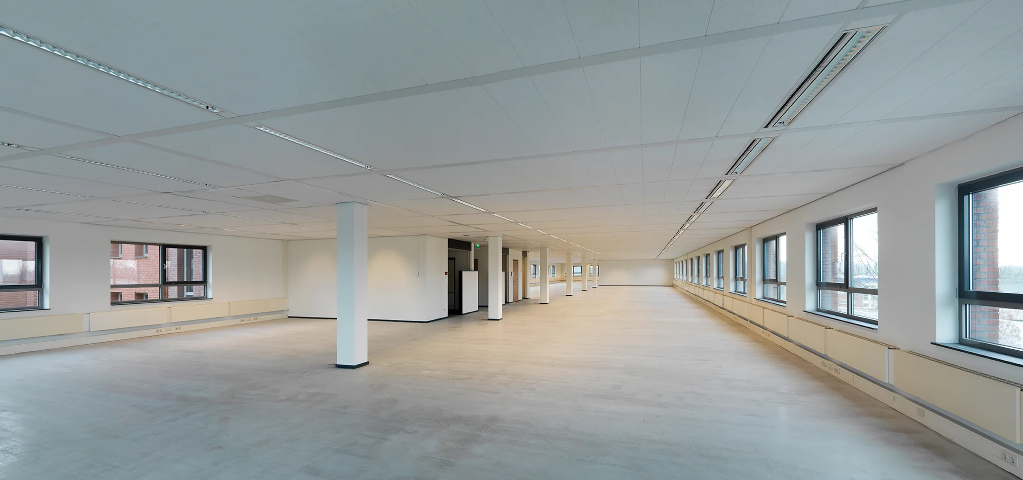 Leeg, licht en ruim kantoorpand aan de Pompmolenlaan met grote ramen en systeemplafond.