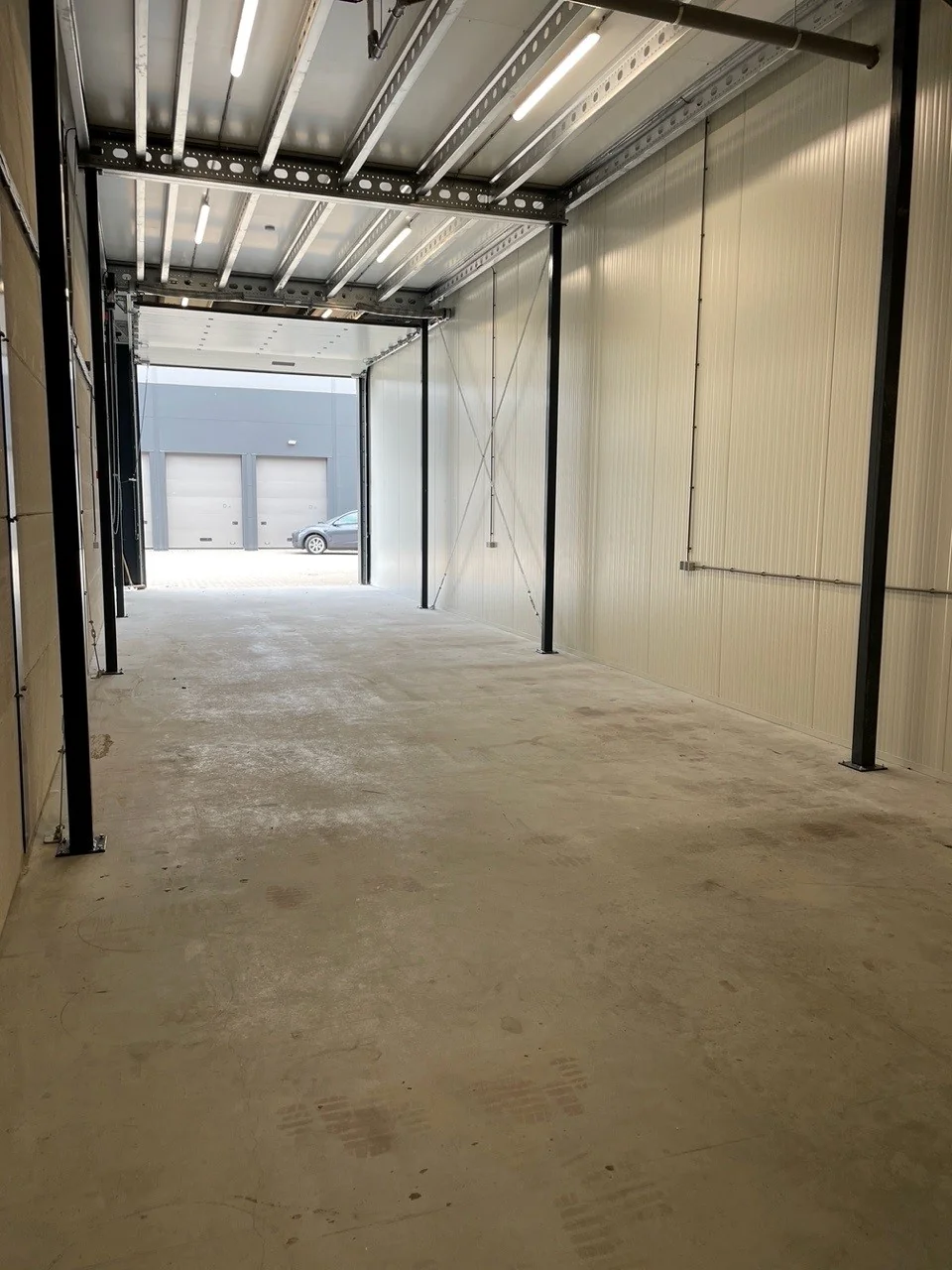 Lege, diepe industriële opslagruimte aan de Aalsmeerderweg met open garagedeur en zicht op het buitenterrein.