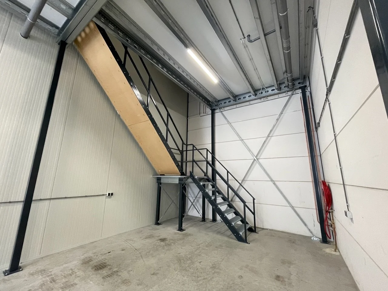 Industriële binnenruimte met een metalen trap naar een entresolvloer aan de Aalsmeerderweg.