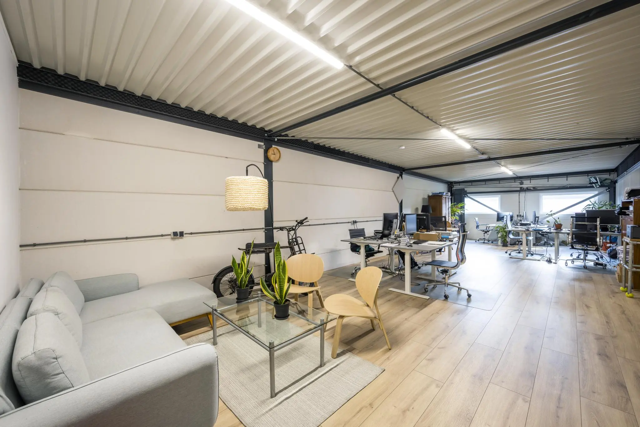 Modern kantoorinterieur aan de Aalsmeerderweg met werkplekken, een zithoek en houten vloer.