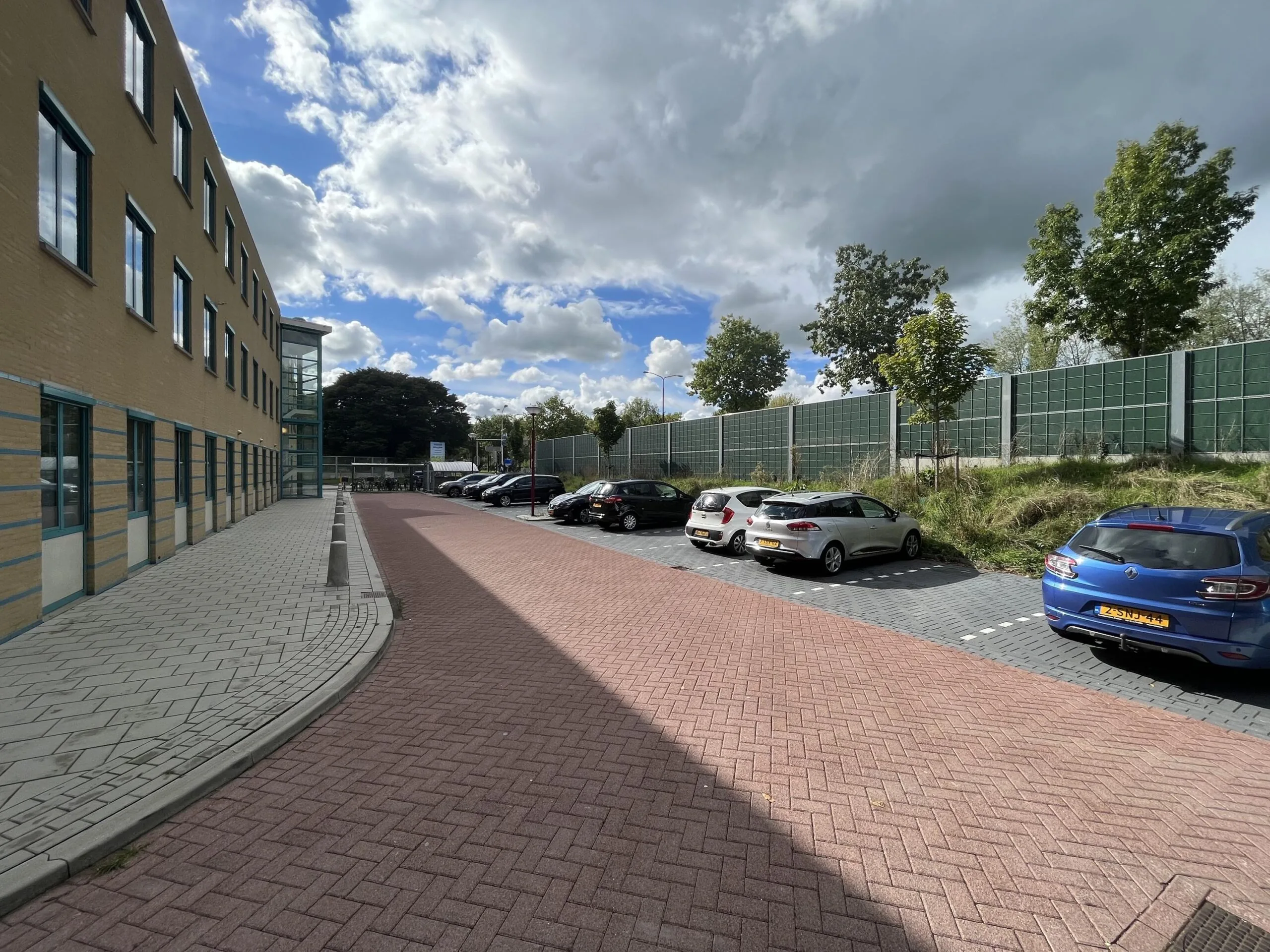 Een rij geparkeerde auto's langs een gebouw aan de Zoutkamper Schans op een bewolkte dag.