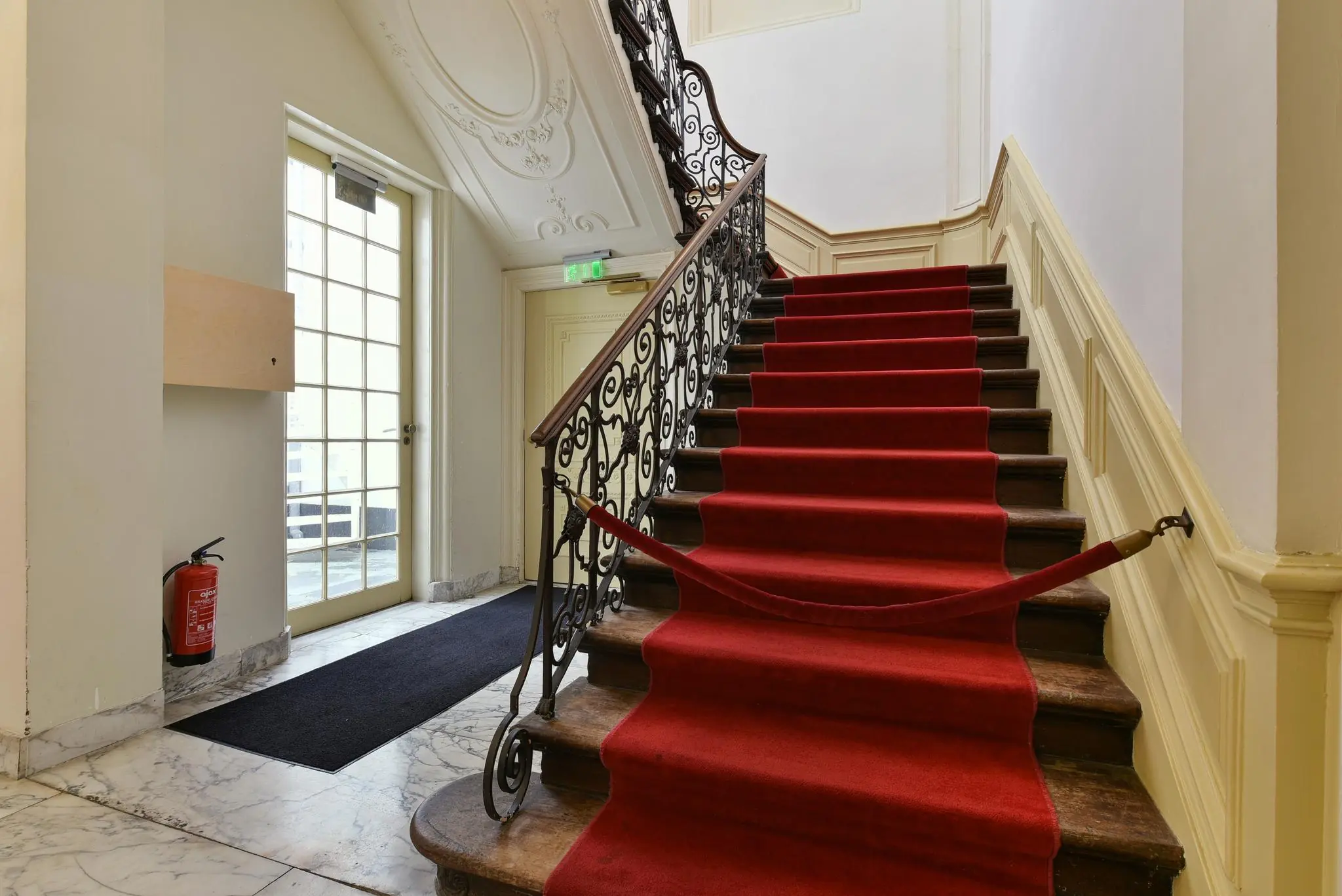 Trappenhuis met rode loper en sierlijke leuning in een klassiek gebouw aan het Rapenburg.