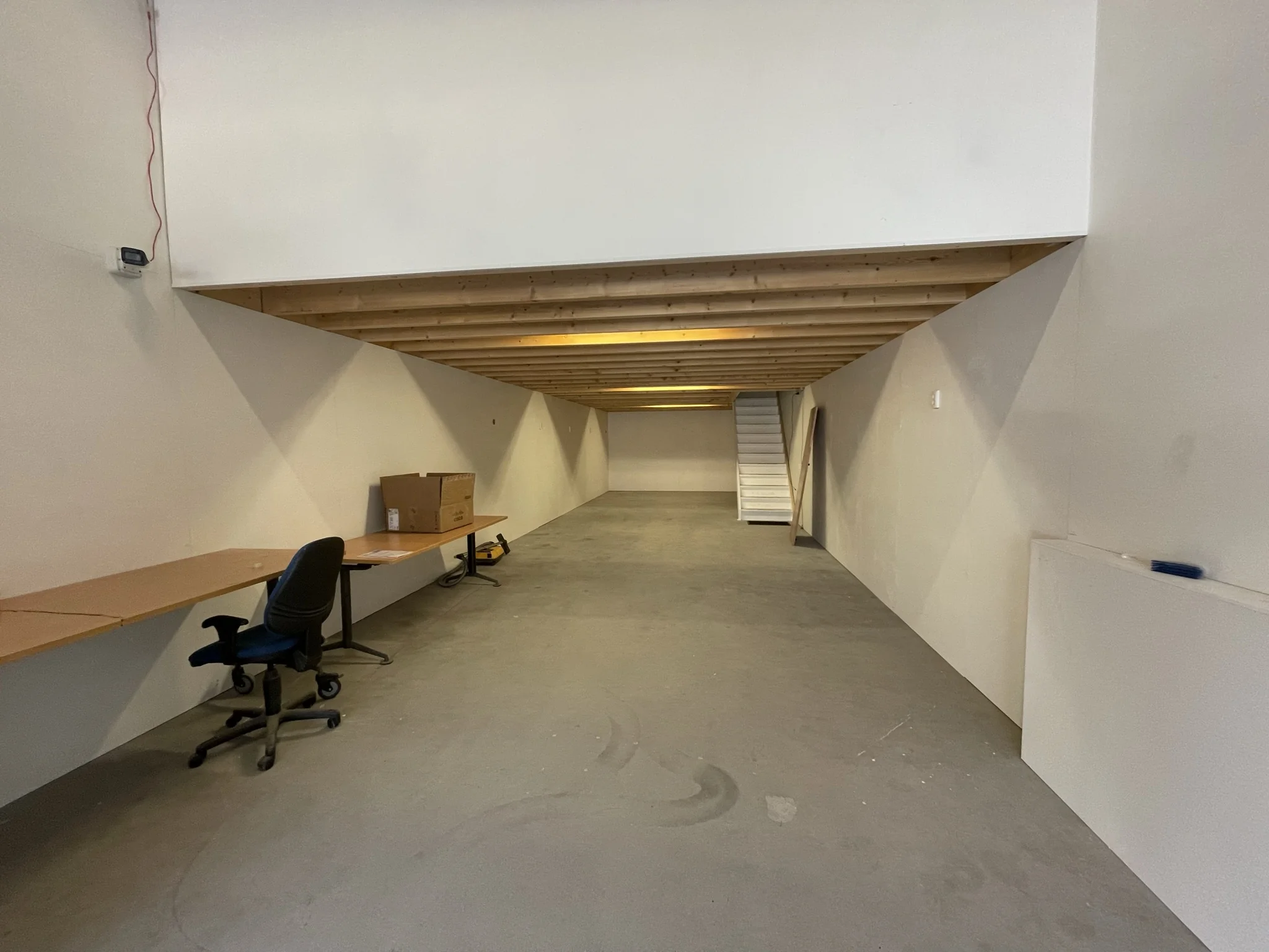 Lege werkruimte aan de Aalsmeerderweg met bureaus, bureaustoel en een houten bovenverdieping met trap.