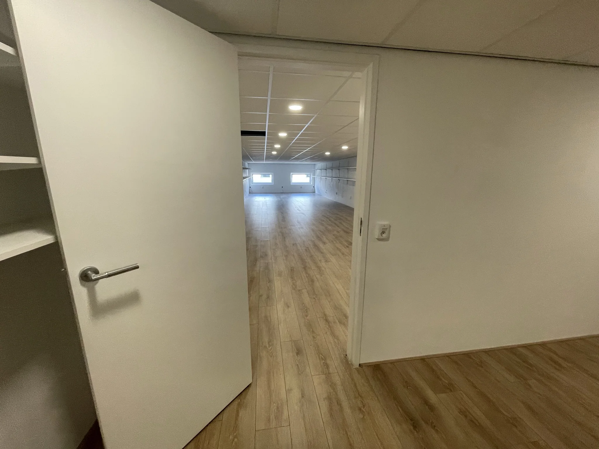 Open deur met zicht op een ruime, lichte kamer met houten vloer aan de Aalsmeerderweg.